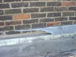 Severely deteriorated flashing at a parapet wall Severely deteriorated flashing at a parapet wall